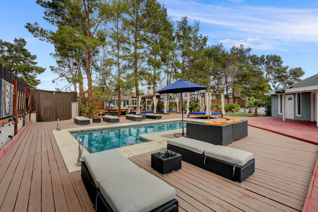 A spacious deck in the backyard of Zen Paradise mansion in Vegas shows several comfy loungers surrounding one of the home's backyard pools in Vegas.