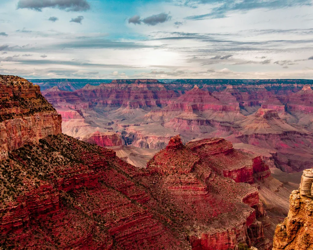 Layers of red rock as far as the eye can see in this view over Grand Canyon National Park, with a sky equally layered in clouds and shades of bllue.