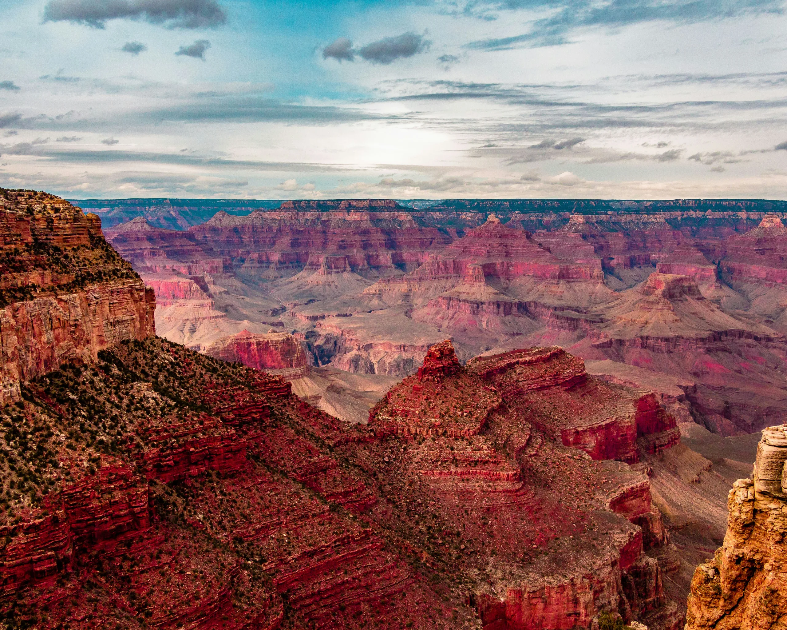 Layers of red rock as far as the eye can see in this view over Grand Canyon National Park, with a sky equally layered in clouds and shades of bllue.